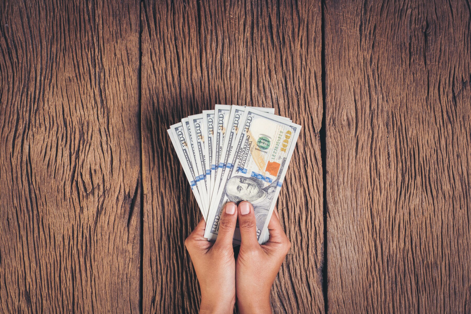 hand-holding-dollar-banknote-money-wood-background_1150-6882